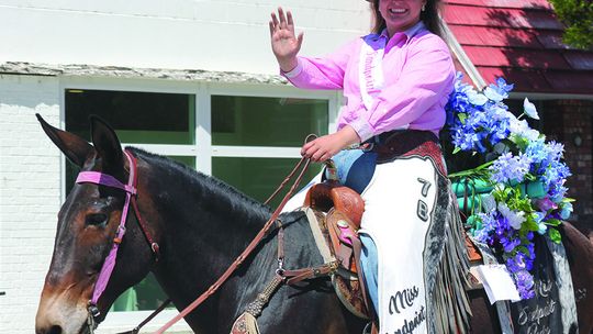 Visiting rodeo royalty wave to the crowd